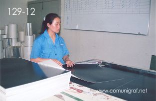 Foto 129-12 - Empleada revisando la calidad de los pliegos laminados con película negra en la planta de Shanghai Xinya Printing Co Ltd de Wenzhou, Shanghai China - 13-Junio-2006