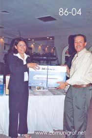 Foto 86-04 - Feliz afortunado con un reproductor de DVD Mitsui, lo entrega Delia Hernández (izq) en la tradicional Comida Baile del día del Impresor de Canagraf Guanajuato, realizada el 24 de Septiembre 2005 en el Hotel La Nueva Estancia de la Ciudad de León, Guanajuato México.