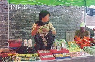Foto 138-18 - Vendedora ofreciendo sus artículos en su puesto de artesanías en la zona del museo de los Guerreros de Terracota en Xiyang cerca de la ciudad de Xían China - 17-Junio-2006